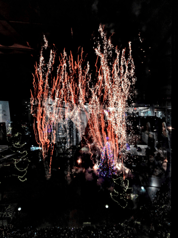 An abstract image of sparkling lights and red lines reflected in dark glass.