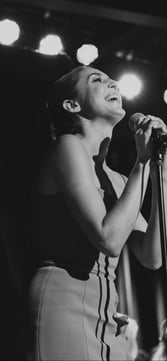 A woman singing while holding a microphone on a stage.