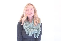 Lauren has blonde hair and is wearing a mint scarf over a grey sweater. She is an engineer for mabl.