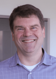 Steve Vance has brown hair and is wearing a lavender, button down shirt.