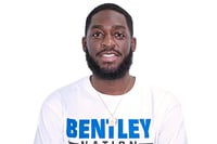 Cornel has black hair and a beard and is wring a white t shirt with the word Bentley on it. He does customer support at mabl.