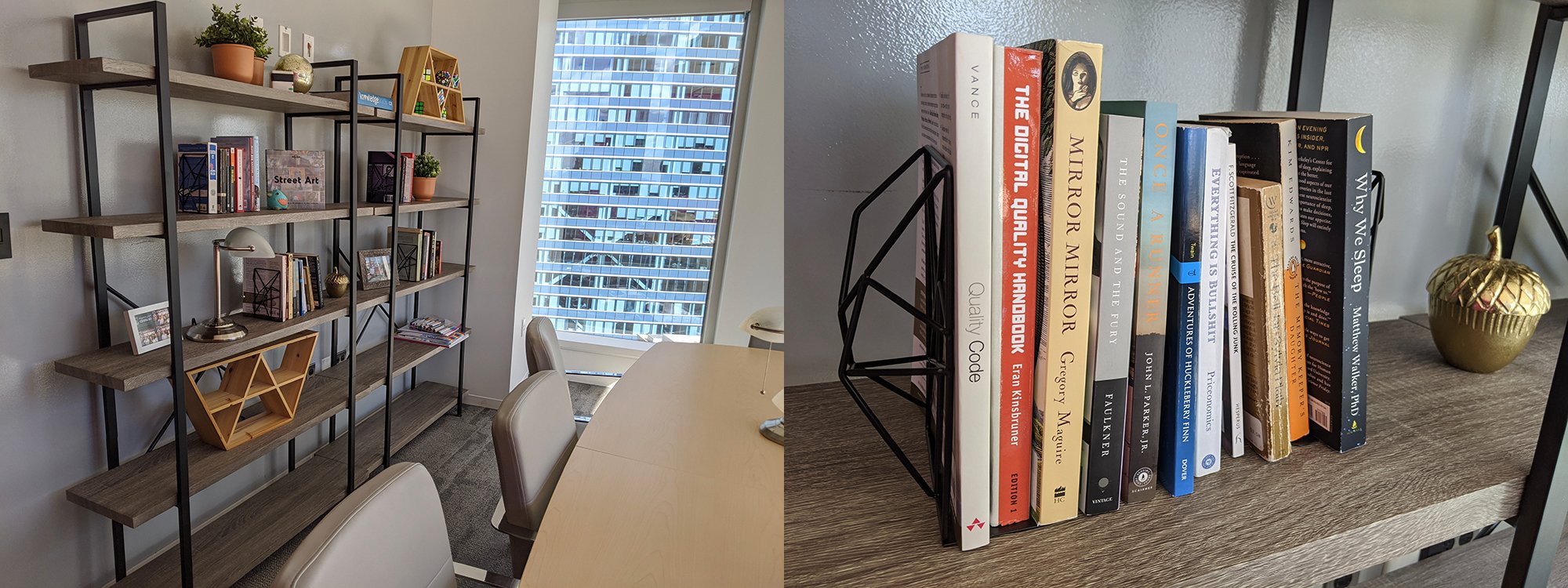 A conference table and a shelf against the wall with books, potted plants and framed pictures.