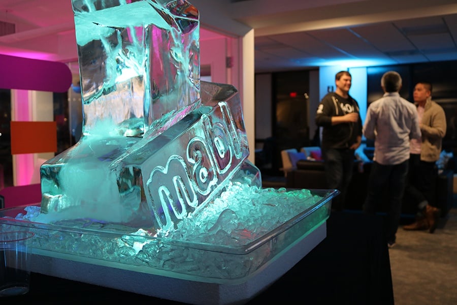 a mabl ice sculpture on a table and 3 men standing in the background, talking to each other.